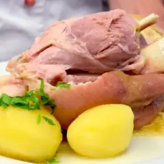 Ein deftiges Eisbein mit Sauerkraut und Kartoffeln, serviert in einem Topf.