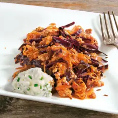 Herzhafte Krautpfanne mit Hackfleisch, serviert mit einem Klecks Kräuterquark und einer Gabel auf einem weißen Teller.