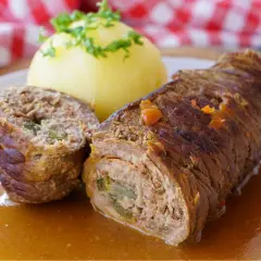 Herzhafte schweinerouladen, gefüllt mit einer herzhaften Mischung, serviert mit Kartoffelklößen und Soße. Welches Fleisch wohl darin steckt?