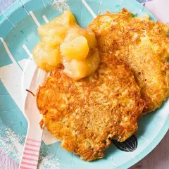 Zwei knusprige Kartoffelpuffer mit Apfelmus, ein herzhaftes Gericht, das an Omas Küche erinnert.