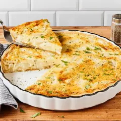 Eine köstliche Spargel Quiche wird serviert. Ein Stück wird mit einem Tortenheber herausgehoben, garniert mit frischer Petersilie.
