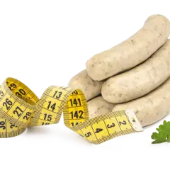 Bratwurst roh essen? Ein Maßband zeigt, dass man auf die Figur achten sollte. Ein Petersilienblatt liegt daneben.