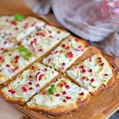 Flammkuchen mit cremigem Belag, Zwiebeln und roten Speckwürfeln. Ein köstlicher Flammkuchen Belag, der Appetit macht.