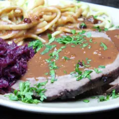 Sauerbraten mit Klößen und Rotkohl. Die Marinierzeit für Sauerbraten kann variieren, oft mehrere Tage.