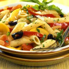 Bunte Nudelgerichte mit Penne, Tomaten, Zucchini, schwarzen Oliven und frischen Kräutern, garniert mit Parmesan.