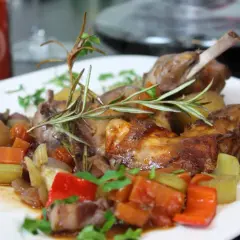 Ein köstlich gebratenes Kaninchen mit Kartoffeln, Karotten und Paprika, garniert mit Rosmarin.