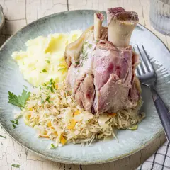 Deftig zubereitetes Eisbein in Sauerkraut kochen, serviert mit Kartoffelpüree und Senf.