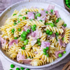 Eine cremige Nudel Schinken Pfanne mit Erbsen und frisch gemahlenem Pfeffer, serviert in einer rustikalen Schüssel.