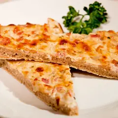 Drei Stücke herzhafter Blooz mit Speck und Zwiebeln auf einem Teller, garniert mit Petersilie. Ein köstliches Blooz-Rezept.
