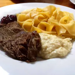 Ein Teller mit deftigem Braten, Bandnudeln, Klößen und Preiselbeeren – ein typisches Hochzeitsessen in Franken.