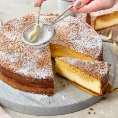 Ein köstlicher Kuchen mit Puderzucker wird bestäubt. Ein Stück wird mit einem goldenen Tortenheber herausgehoben. Dreh dich um, Kuchen, du siehst lecker aus!