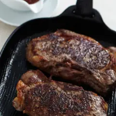 Zwei saftige Rumpsteaks braten in einer Grillpfanne, perfekt gewürzt und mit einer köstlichen Kruste.