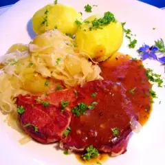 Gekochte Rippchen zubereiten: Herzhaftes Gericht mit deftigen Rippchen, Sauerkraut und Kartoffeln, garniert mit Petersilie und blauen Blüten.