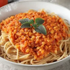 Herzhafte Linsen Bolognese auf Vollkornspaghetti, garniert mit frischen Kräutern. Ein köstliches, vegetarisches Gericht.