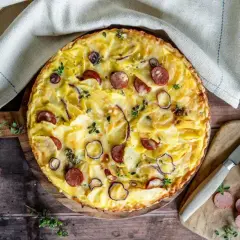 Herzhafte Kartoffeltorte mit Speck und Zwiebeln, goldbraun gebacken und mit frischen Kräutern garniert. Ein Genuss für jeden Anlass.