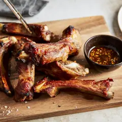 Saftige schweinerippchen braten, glasiert und mit Dip auf Holzbrett. Perfekt zum Genießen!