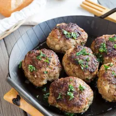 Sechs goldbraune Fleischpflanzerl, frisch aus der Pfanne, garniert mit Petersilie. Ein leckeres Fleischpflanzerl Rezept zum Nachkochen.