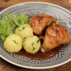 Saftiger Hasenbraten Hausfrauenart mit Klößen, Salat und dunkler Soße auf einem gemusterten Teller.