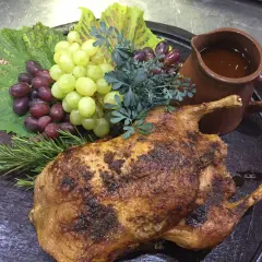Gefüllte Ente mit Trauben und Rosmarin, serviert mit einer Sauce. Ein Festmahl, das an Schlehen Rezepte erinnert.