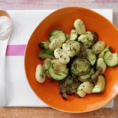 Gnocchi mit Zucchini und Pilzen in einer orangen Schüssel, dazu ein Löffel cremiger Dip. Eine köstliche zucchini pfanne.