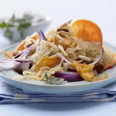 Ein Teller mit gebratenem Sauerkraut, garniert mit roten Zwiebeln, Rosinen und Mandelsplittern.