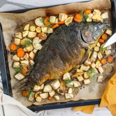 Schuppenkarpfen zubereiten: Ganzer Fisch mit Wurzelgemüse und Zitrone auf einem Blech gebacken. Daneben gekochte Kartoffeln.