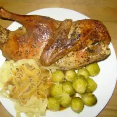 Halbe Ente braten, goldbraun und knusprig, serviert mit Bandnudeln und Rosenkohl. Ein Festmahl!