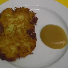 Zwei knusprige Kartoffelpuffer liegen auf einem Teller neben einem Klecks Apfelmus.