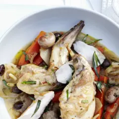 Ein köstliches Gericht mit zartem wirsing kaninchen, Karotten, Oliven und Kräutern in einer aromatischen Sauce, serviert in einer weißen Schüssel.