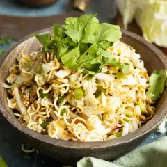 Ein köstlicher mie nudelsalat mit knackigem Kohl, Frühlingszwiebeln und frischem Koriander, garniert mit Sesam.