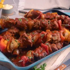 Herzhaftes Schaschliktopf Rezept: Fleischspieße mit Paprika und Zwiebeln in würziger Tomatensauce, serviert mit Pommes.