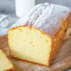 Ein saftiger Rührkuchen, bestäubt mit Puderzucker, ideal für einfache Kuchen Rezepte. Daneben liegen zwei Scheiben.