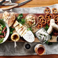 Herzhafte deutsche Gerichte: Wurst, Käse, Brezeln, Salat und Brot auf rustikaler Platte.