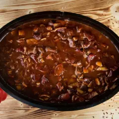 Herzhaftes Gulasch im Dutch Oven, ein Klassiker der Dutch Oven Rezepte. Daneben liegt eine rote Paprika.