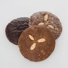 Drei runde Elisenlebkuchen, einer schokoladenüberzogen, die anderen mit Mandeln verziert. Beste Elisenlebkuchen für den Genuss.