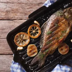 Gegrillter Karpfen mit Zitrone und Rosmarin auf einer Grillpfanne. Ein köstliches Beispiel für Karpfen Gerichte.
