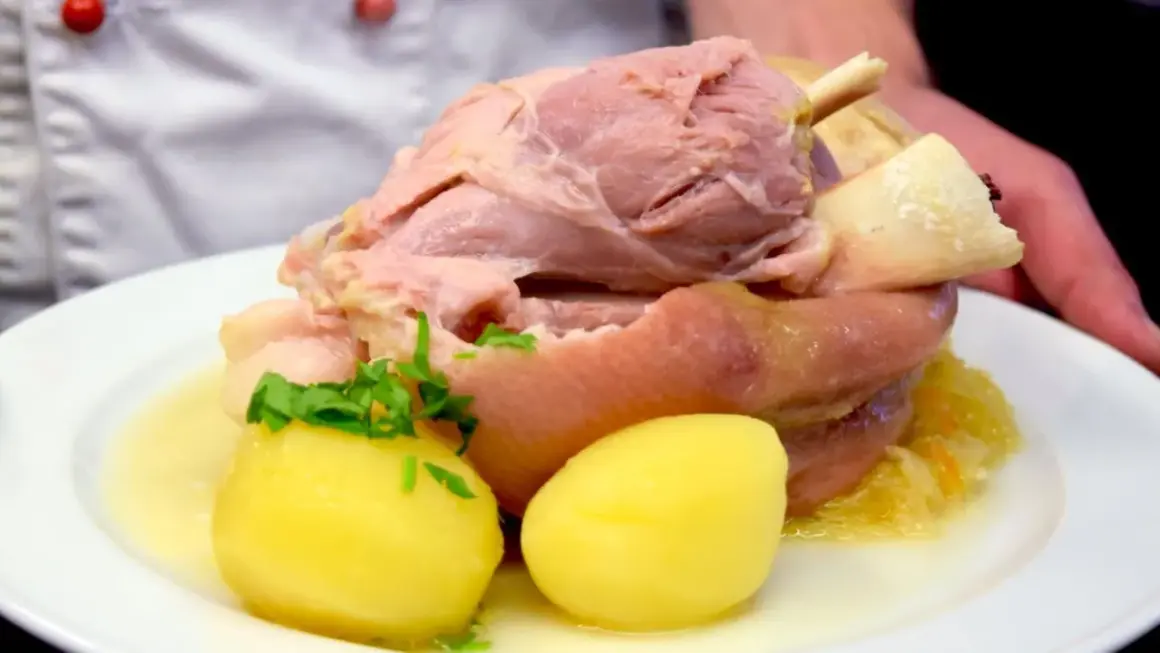 Ein deftiges Eisbein mit Sauerkraut und Kartoffeln, serviert in einem Topf.