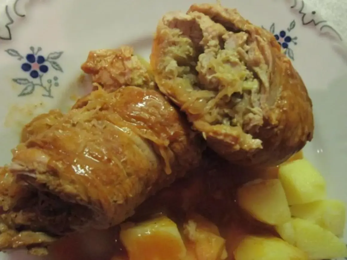 Zwei saftige Rouladen, gefüllt mit einer herzhaften Mischung, serviert mit Kartoffeln und einer köstlichen Sauce. Ein klassisches Gericht, das an ein deftiges Schnitzel mit Sauerkraut erinnert.