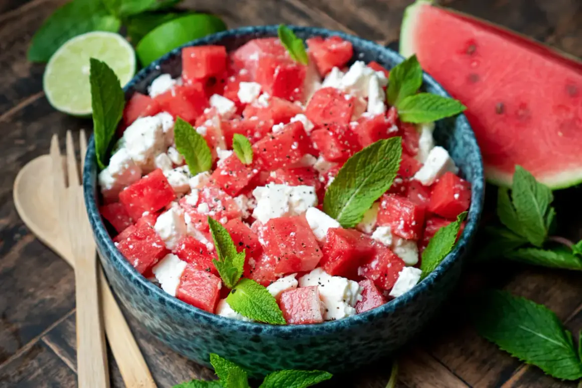 Erfrischender sommerlicher Melonensalat mit Feta und Minze, garniert mit Limettenspalten und einem Holzlöffel.