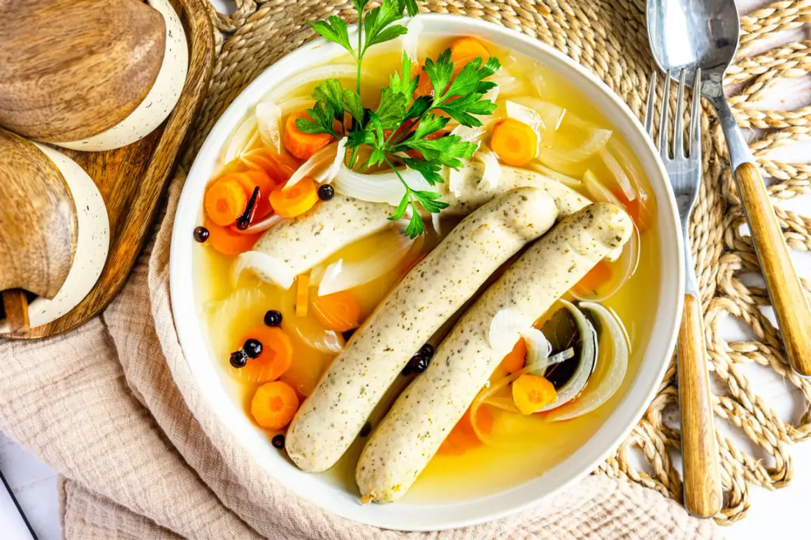 Herzhaftes rezept blaue zipfel: zwei Würste in Brühe mit Karotten, Zwiebeln und Petersilie.