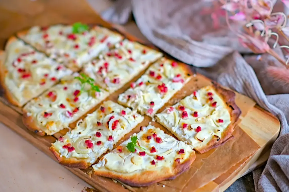 Flammkuchen mit cremigem Belag, Zwiebeln und roten Speckwürfeln. Ein köstlicher Flammkuchen Belag, der Appetit macht.