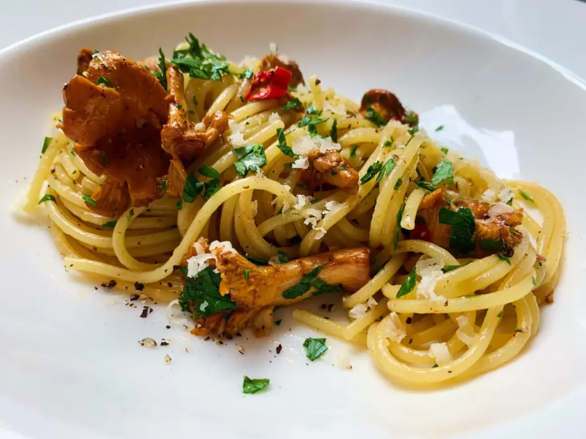 Pfifferling Nudeln mit frischer Petersilie und Parmesan. Ein köstliches Gericht, das den Geschmack des Waldes auf den Teller bringt.