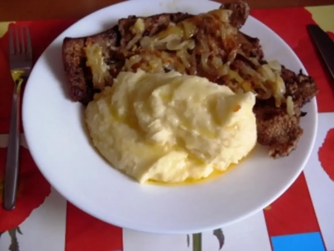 Herzhaft gebratene Leber mit Zwiebeln und cremigem Kartoffelbrei auf einem Teller. Ein Klassiker, der Appetit macht.