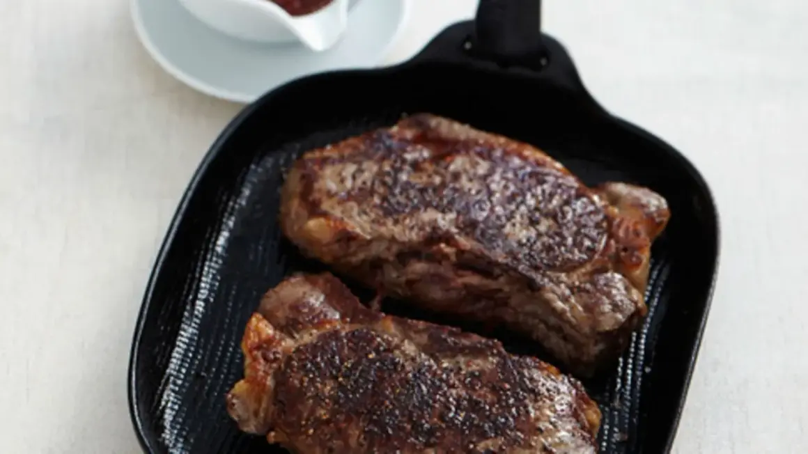 Zwei saftige Rumpsteaks braten in einer Grillpfanne, perfekt gewürzt und mit einer köstlichen Kruste.