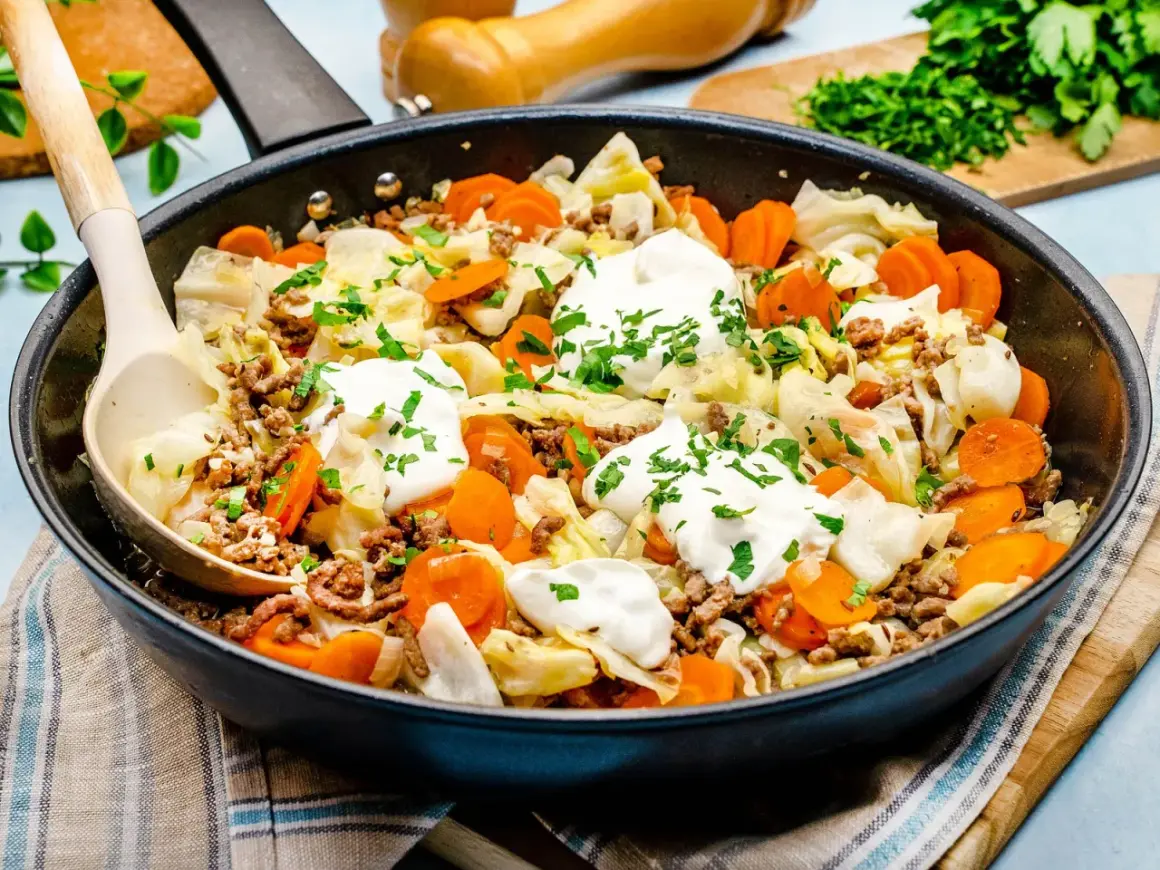 Herzhaftes spitzkohl mit hackfleisch in der Pfanne, garniert mit Klecksen saurer Sahne und Petersilie. Ein deftiges Gericht!