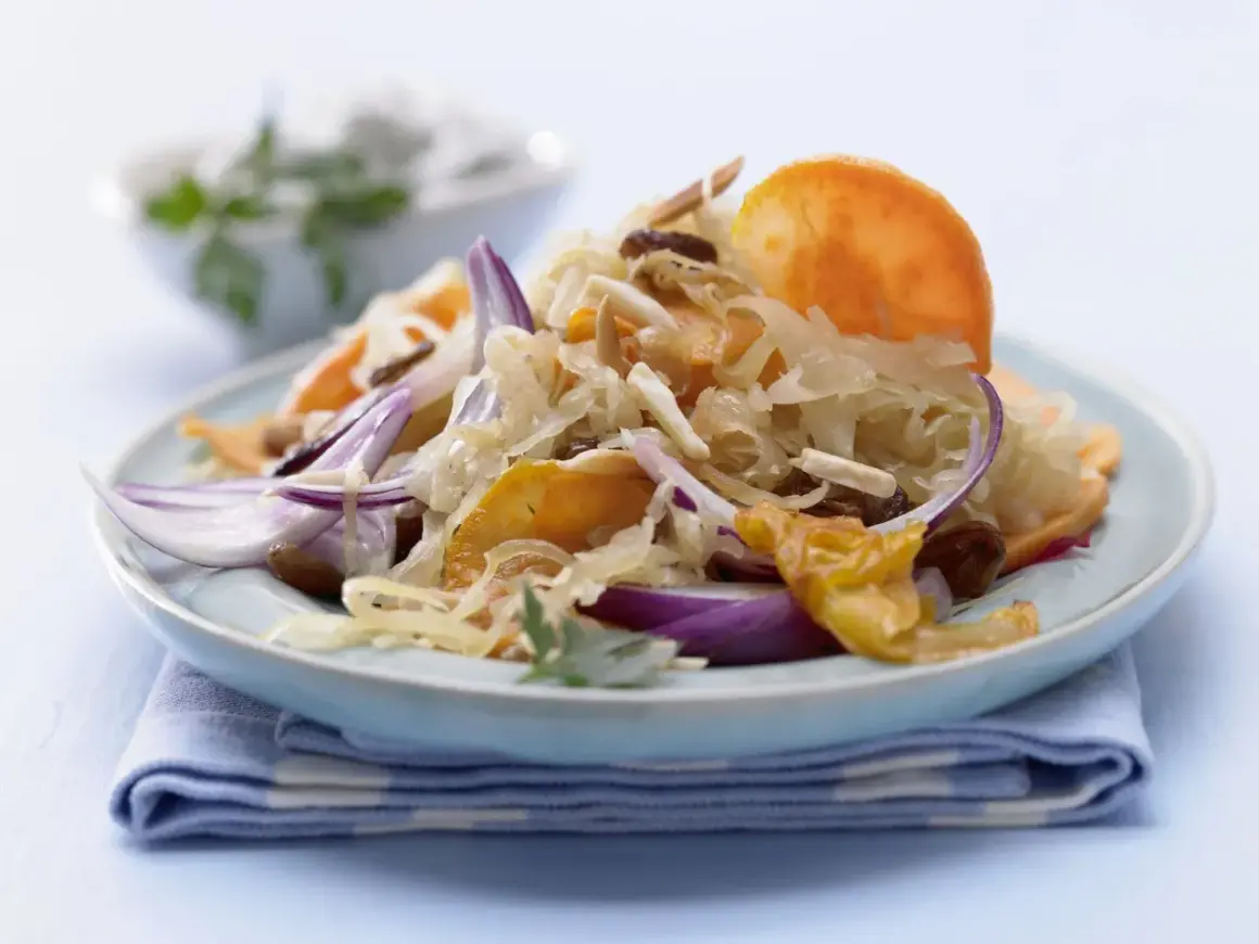 Ein Teller mit gebratenem Sauerkraut, garniert mit roten Zwiebeln, Rosinen und Mandelsplittern.