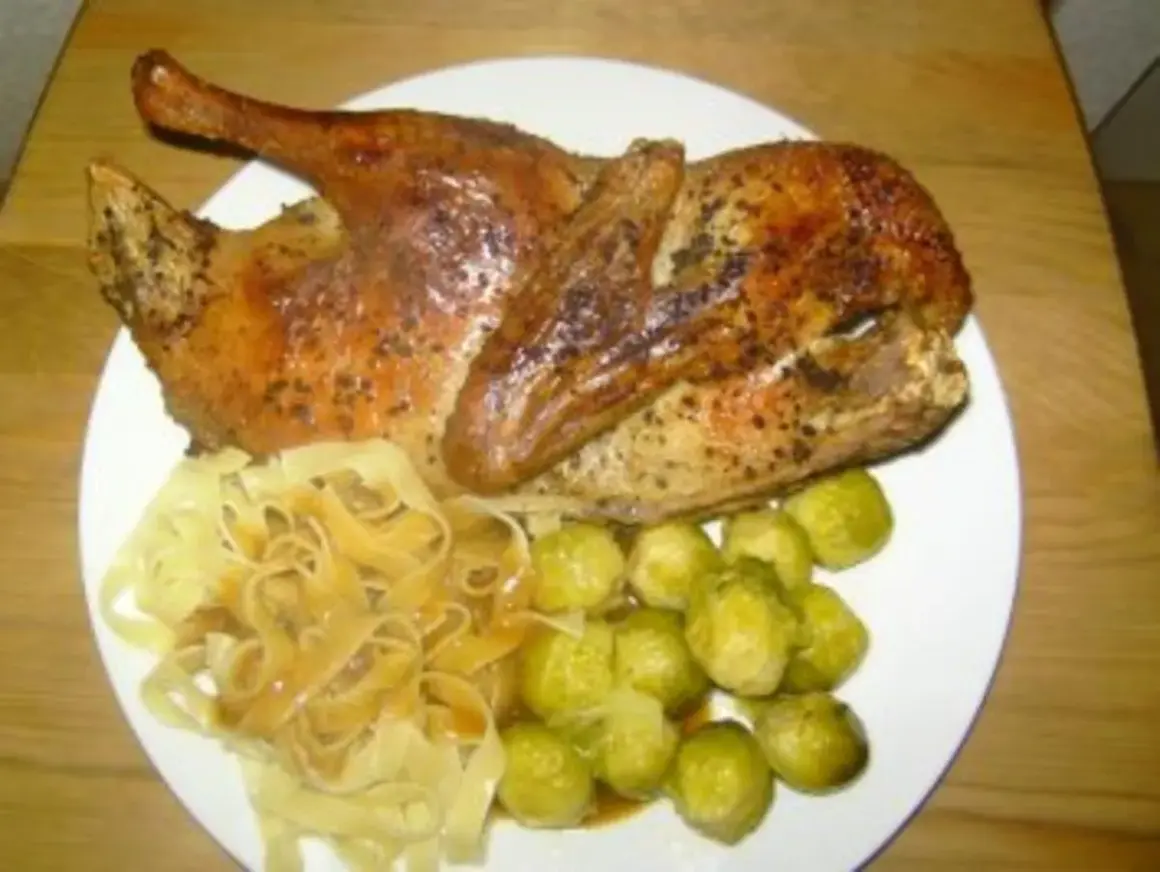 Halbe Ente braten, goldbraun und knusprig, serviert mit Bandnudeln und Rosenkohl. Ein Festmahl!