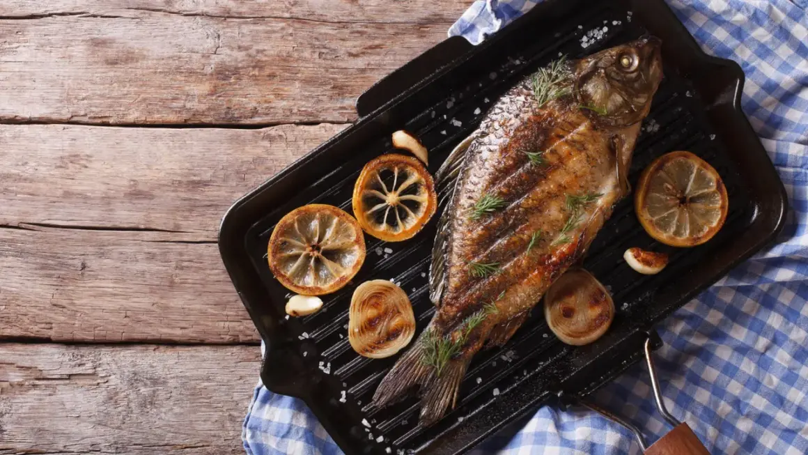 Gegrillter Karpfen mit Zitrone und Rosmarin auf einer Grillpfanne. Ein köstliches Beispiel für Karpfen Gerichte.