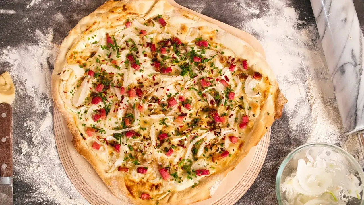 Flammkuchen-Rezept: knuspriger Teig mit Zwiebeln, Speck und Kräutern, bereit zum Genuss.