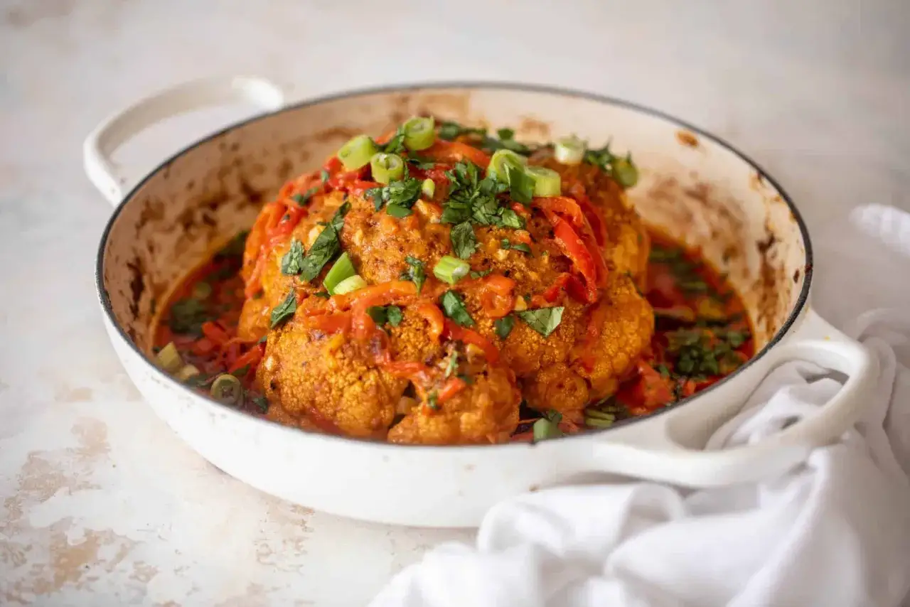 Ganzes Blumenkohlgericht in einer Pfanne, mit Paprika und Kräutern garniert. Ein köstliches Beispiel für Blumenkohl Rezepte.
